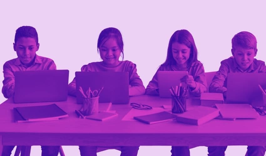 Students writing on laptops together at a classroom table
